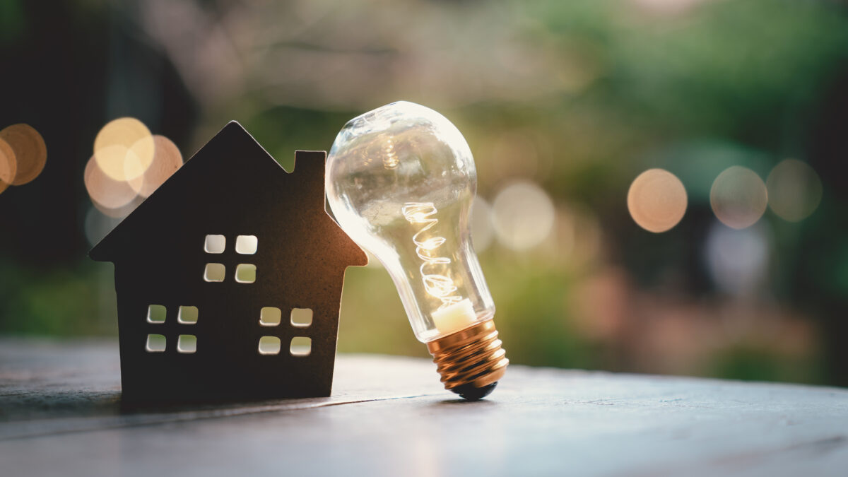 Light bulb with wood house on the table, a symbol for construction, Creative light bulb idea, power energy or business idea concept ecology, loan, mortgage, property or home