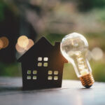 Light bulb with wood house on the table, a symbol for construction, Creative light bulb idea, power energy or business idea concept ecology, loan, mortgage, property or home