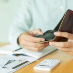 close up man hand opening empty wallet over calculator , debt expense bills monthly and credit card at the table in home office , managing payroll,money risk financial concept