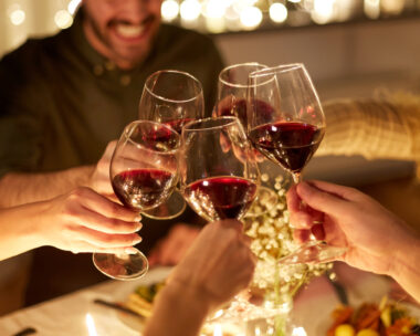 holidays, celebration and people concept - happy friends having christmas dinner at home drinking non-alcoholic red wine