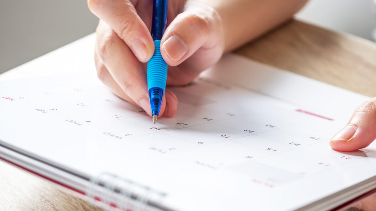 Woman hand with pen writing on calendar date business planning appointment meeting concept