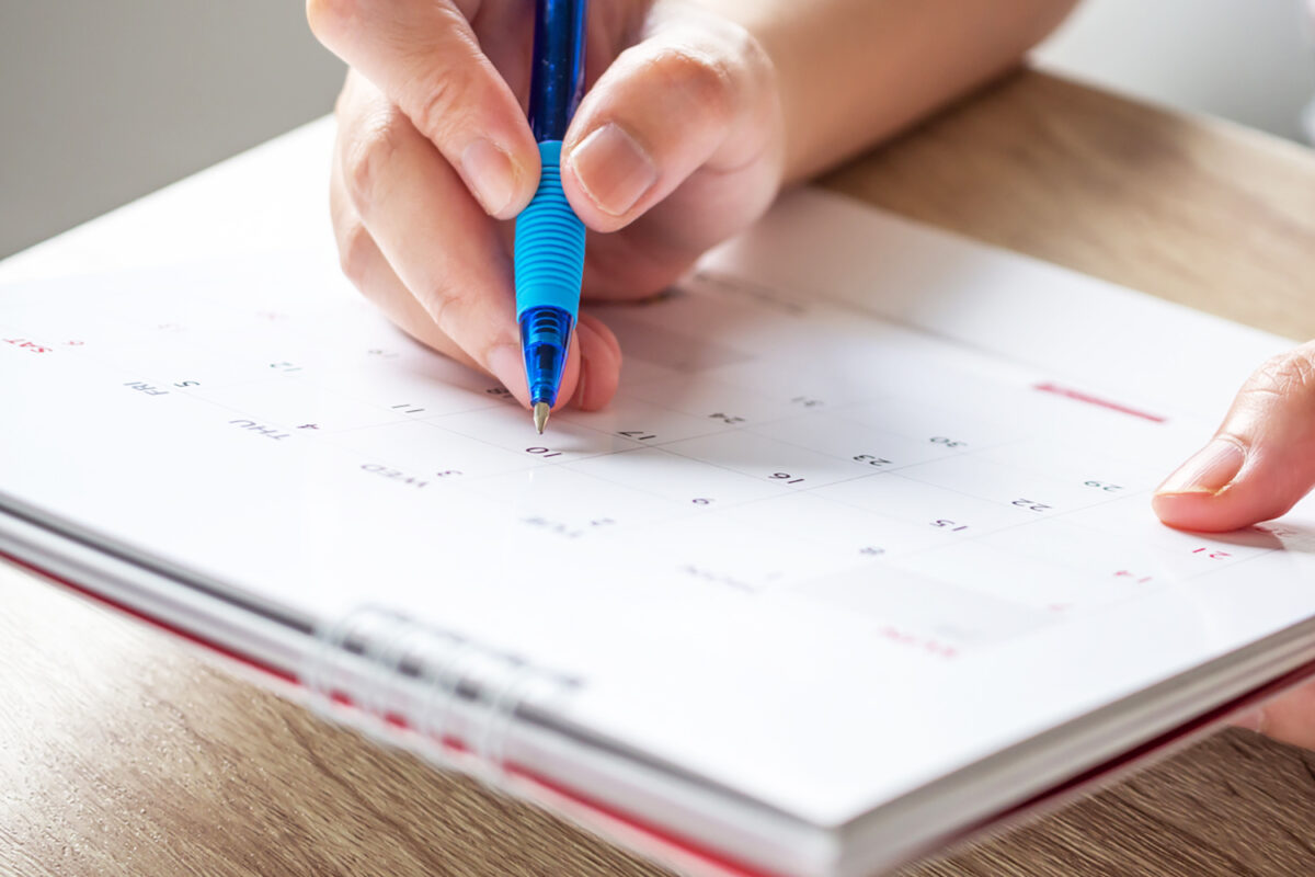 Woman hand with pen writing on calendar date business planning appointment meeting concept