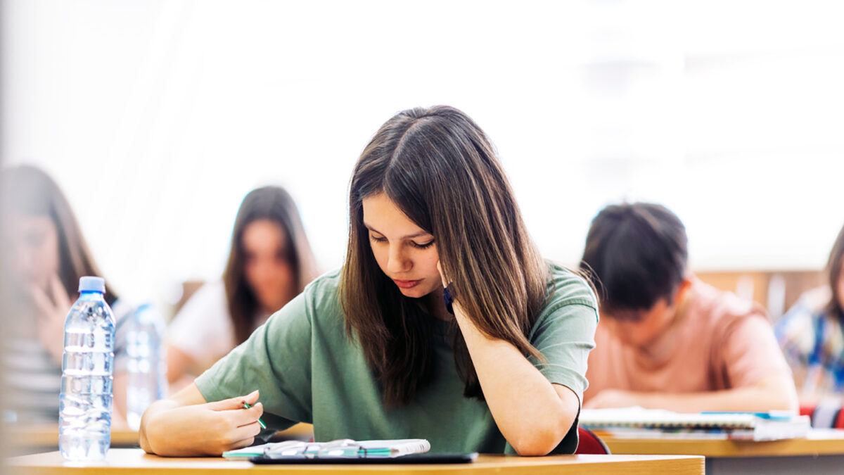 Teenage students sitting in school's classroom and learning. They are using tablet and studying with good concentration in their modern school.