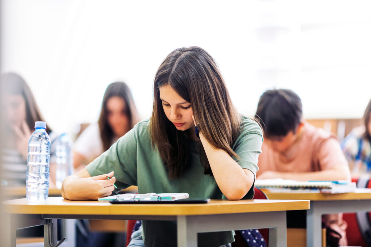 Teenage students sitting in school's classroom and learning. They are using tablet and studying with good concentration in their modern school.