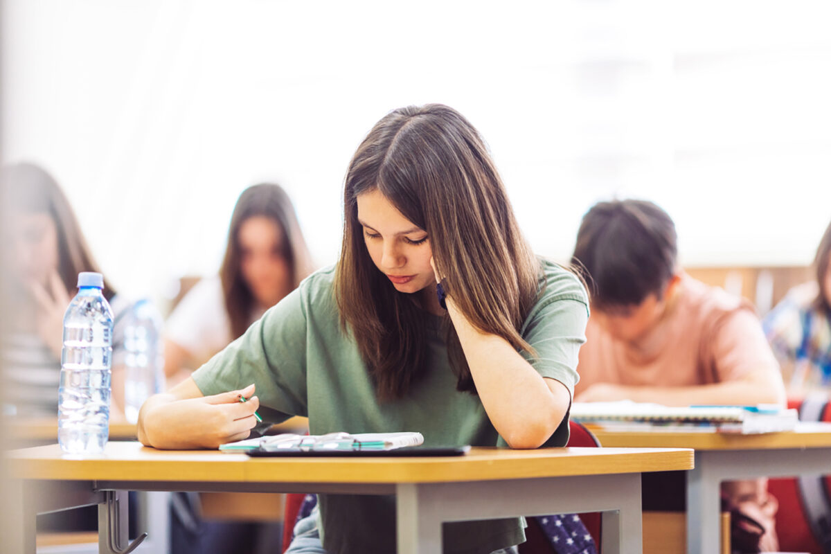 Teenage students sitting in school's classroom and learning. They are using tablet and studying with good concentration in their modern school.
