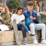Four teenagers chatting on their smartphone on walking