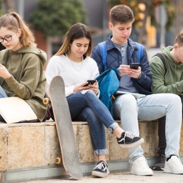 Four teenagers chatting on their smartphone on walking