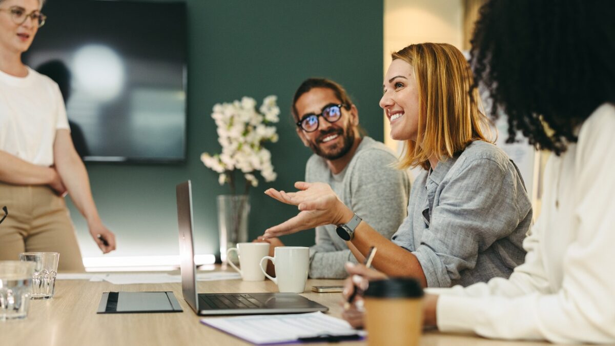 Business woman talking to her colleagues during a meeting in a boardroom. Group of happy business people working together in a creative office