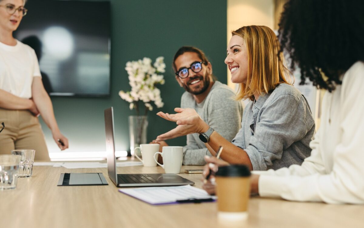 Business woman talking to her colleagues during a meeting in a boardroom. Group of happy business people working together in a creative office