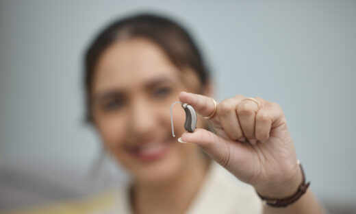 Hearing aid, hands and person with disability for medical support, listening and healthcare innovation. Closeup of deaf female patient with audiology implant to help sound waves, amplifier and volume