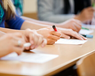 Close-up of writing hands of students at course