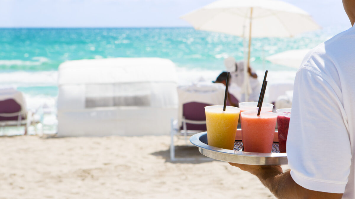 Waiter brings cocktail to resort guests on the beach