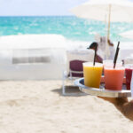 Waiter brings cocktail to resort guests on the beach