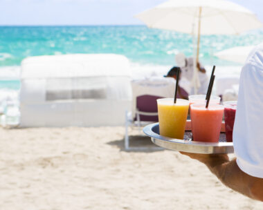 Waiter brings cocktail to resort guests on the beach