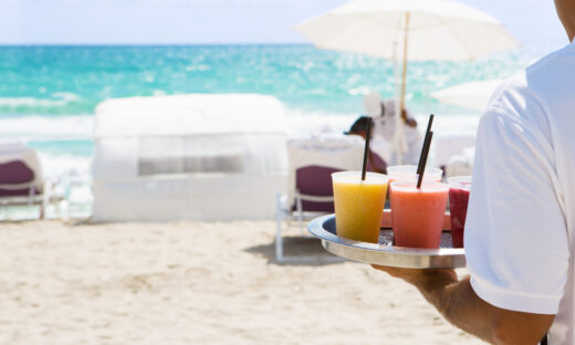Waiter brings cocktail to resort guests on the beach