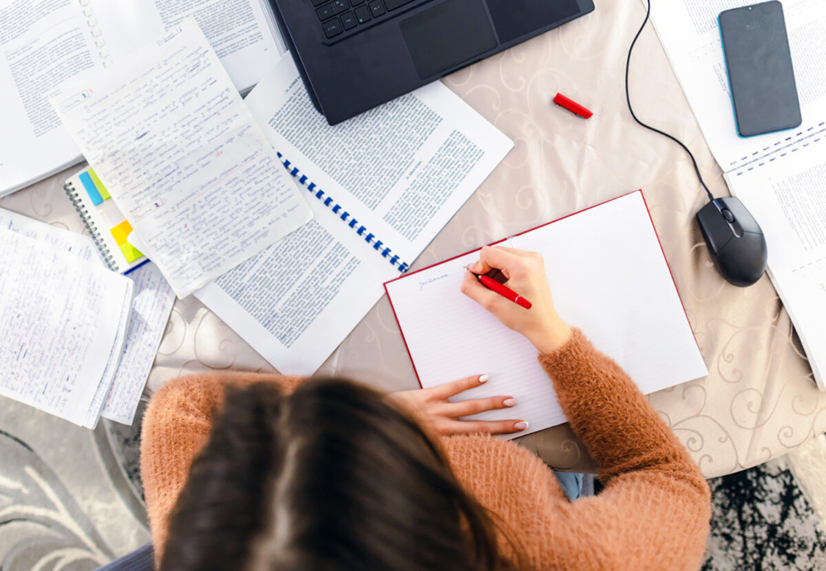 A young woman sitting at a desk in her home, earnestly studying for an upcoming exam.