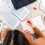 A young woman sitting at a desk in her home, earnestly studying for an upcoming exam.