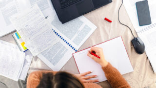 A young woman sitting at a desk in her home, earnestly studying for an upcoming exam.