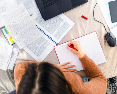 A young woman sitting at a desk in her home, earnestly studying for an upcoming exam.