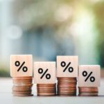 Interest rate finance and mortgage rates. Wooden block with percentage sign on many level of stack of coin. Financial growth, interest rate increase, inflation, sale price and tax rise concept.