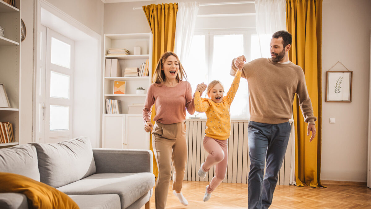 Happy family, mother, father and daughter jumping and playing at home.