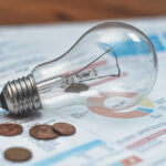 Detail of electricity bills with light bulb and coins