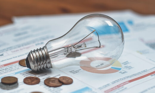 Detail of electricity bills with light bulb and coins
