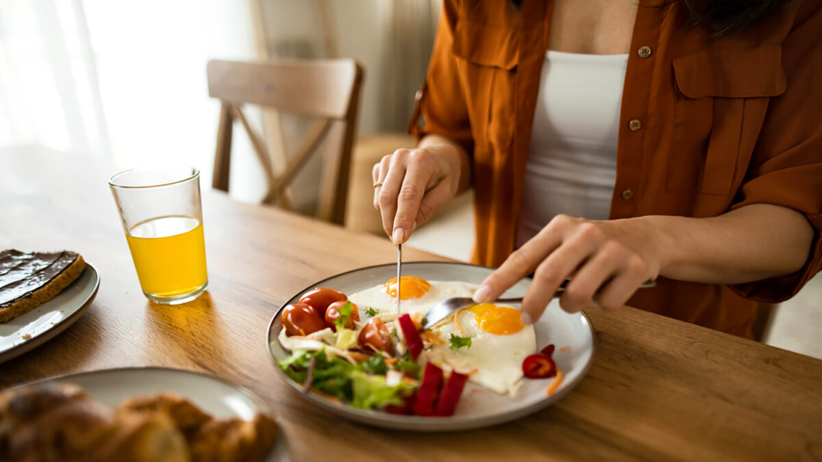 Hand close-up of woman eating breakfast at home.