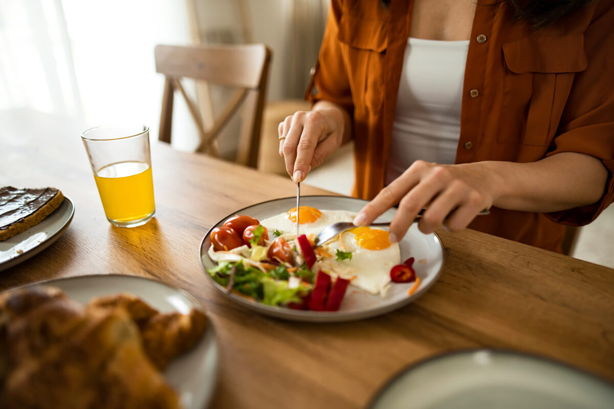 Hand close-up of woman eating breakfast at home.