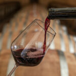 Pouring red wine into the glass in the cellar