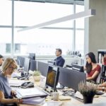 Business people working at desk. Male and female professionals are sitting by windows. Colleagues are sitting in textile industry.