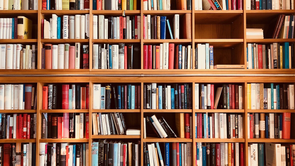 Brown wooden shelfs fully packed with books in a library
