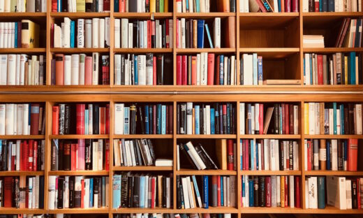 Brown wooden shelfs fully packed with books in a library