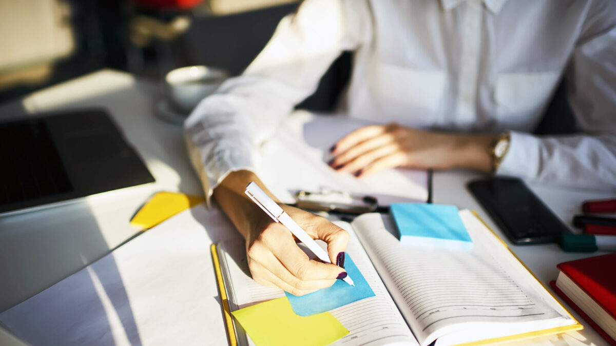 Cropped image of creative female secretary creating planning for executive noting important meeting and events organizing work of busy boss while sitting at working place in coworking office
