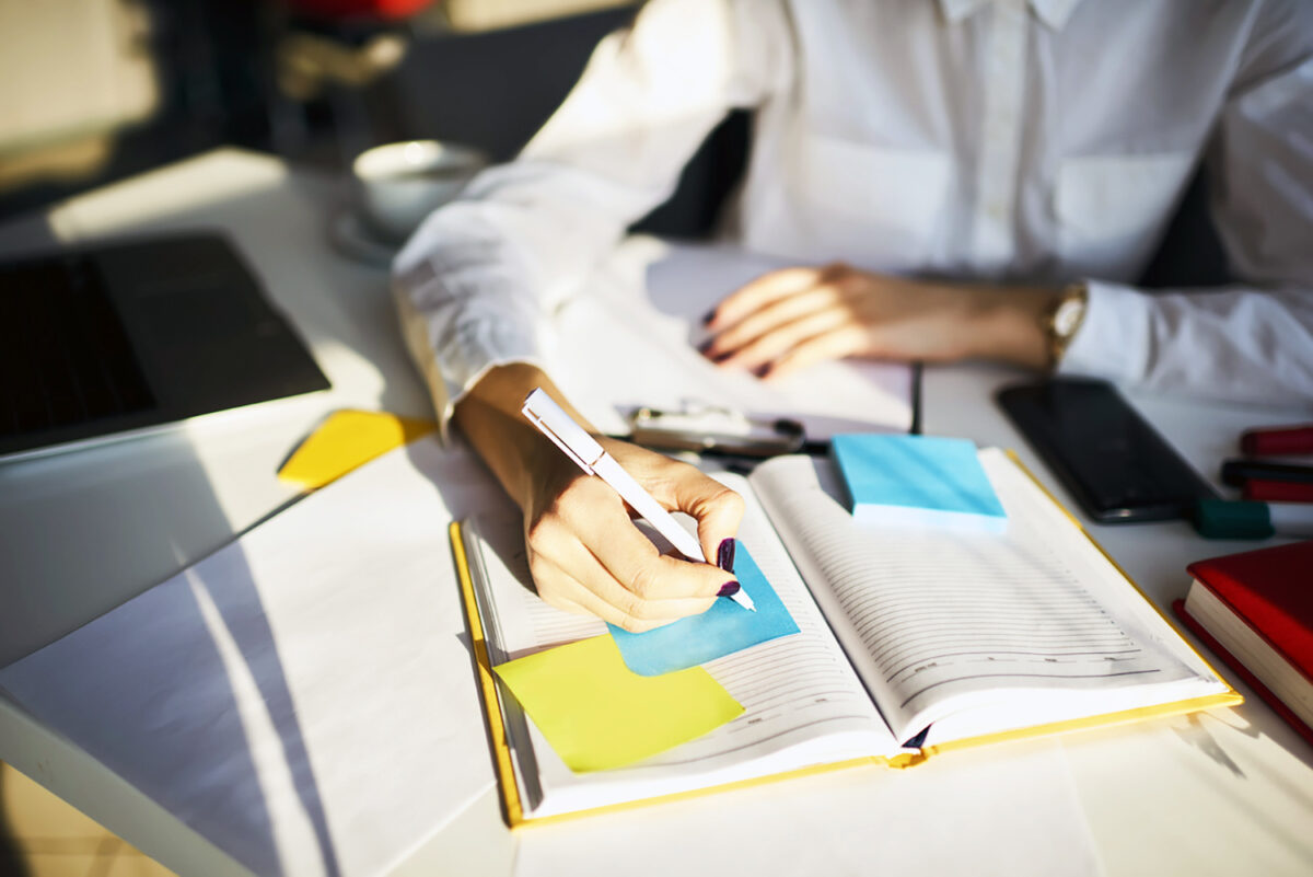 Cropped image of creative female secretary creating planning for executive noting important meeting and events organizing work of busy boss while sitting at working place in coworking office