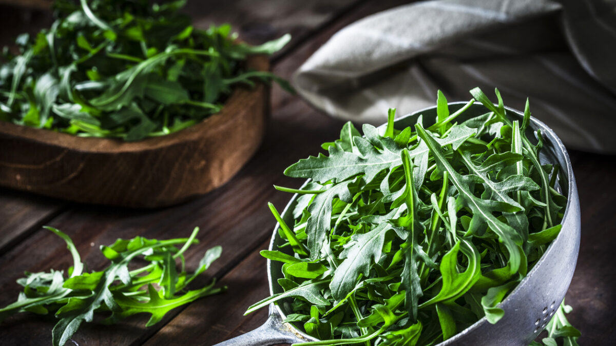 Fresh organic arugula in an old metal colander shot on rustic wooden table. This vegetable is considered a healthy salad ingredient. Predominant colors are green and brown. Low key DSRL studio photo taken with Canon EOS 5D Mk II and Canon EF 100mm f/2.8L Macro IS USM
