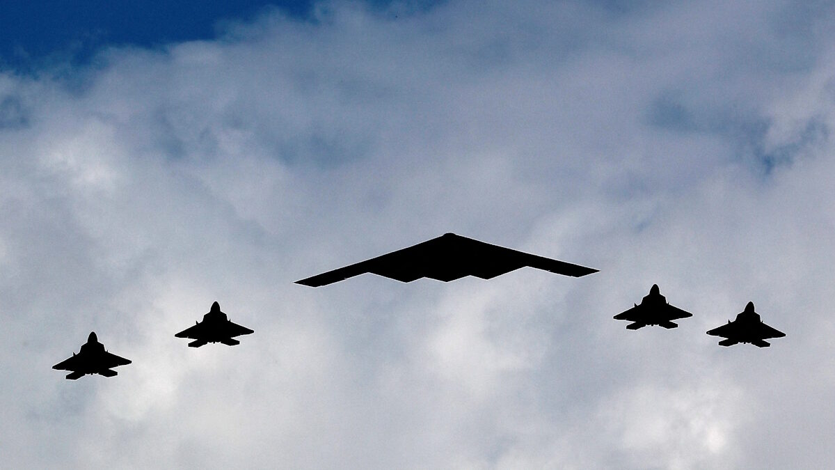 Ένα βομβαρδιστικό B-2 Spirit Stealth πλαισιώνεται από τέσσερα μαχητικά αεροσκάφη F-22 Raptor