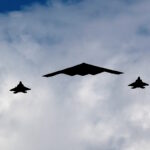 Ένα βομβαρδιστικό B-2 Spirit Stealth πλαισιώνεται από τέσσερα μαχητικά αεροσκάφη F-22 Raptor