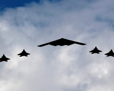 Ένα βομβαρδιστικό B-2 Spirit Stealth πλαισιώνεται από τέσσερα μαχητικά αεροσκάφη F-22 Raptor