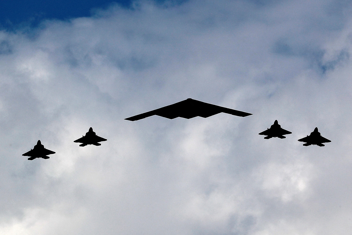 Ένα βομβαρδιστικό B-2 Spirit Stealth πλαισιώνεται από τέσσερα μαχητικά αεροσκάφη F-22 Raptor