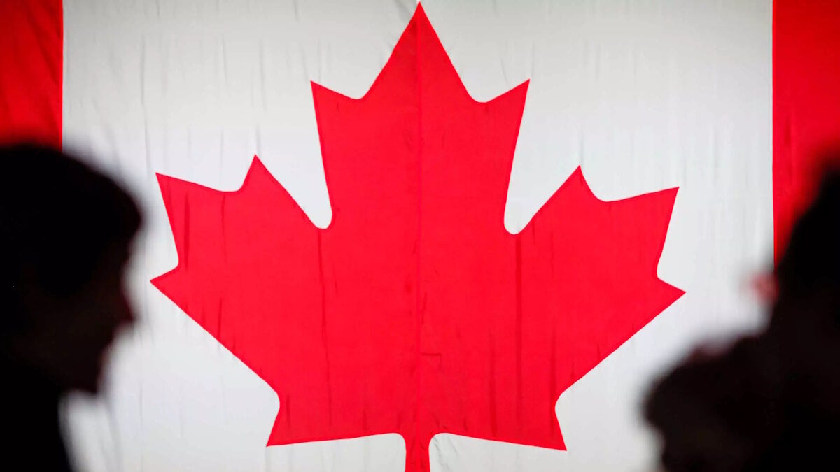 People are silhouetted in front of the Canadian national flag at the Palais des Congres in Montreal, Quebec, Canada October 21, 2019.