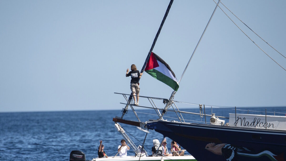 Η ακτιβίστρια για το κλίμα Γκρέτα Τούνμπεργκ στέκεται δίπλα σε παλαιστινιακή σημαία μετά την επιβίβασή της στο πλοίο Madleen και πριν αποπλεύσει για τη Γάζα μαζί με ακτιβιστές του Συνασπισμού Στόλου της Ελευθερίας