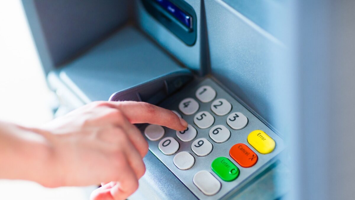 Close-up of hand entering PIN/pass code for a money transfer, on a ATM/bank machine keypad outside