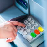 Close-up of hand entering PIN/pass code for a money transfer, on a ATM/bank machine keypad outside