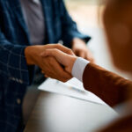 Close up of coworkers handshaking while greeting during business meeting in the office