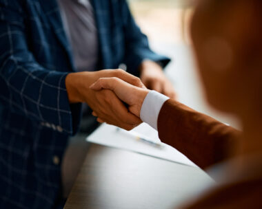 Close up of coworkers handshaking while greeting during business meeting in the office