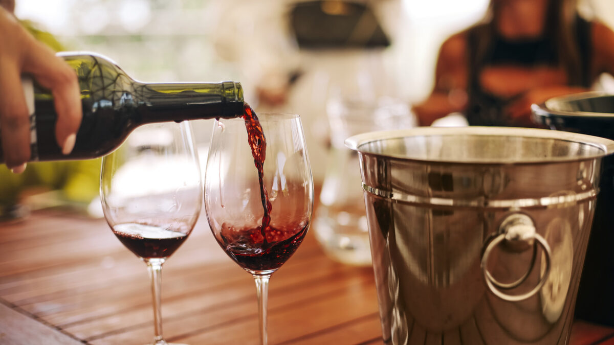 Glasses with different types of wine and human hands holding wine glasses in the background. Degustation wine
