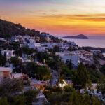 Sunset on Kalymnos, Greece. View over the village of Massouri to the sea with orange colored sky of the setting sun