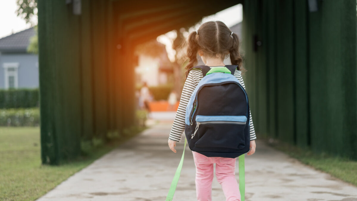 Kid girl pupil walking back to home after learning study school alone with schoolbag,preschool and kindergarten education concept.