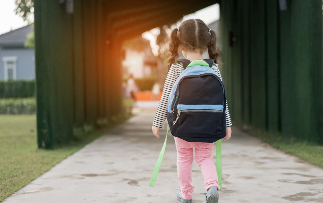 Kid girl pupil walking back to home after learning study school alone with schoolbag,preschool and kindergarten education concept.